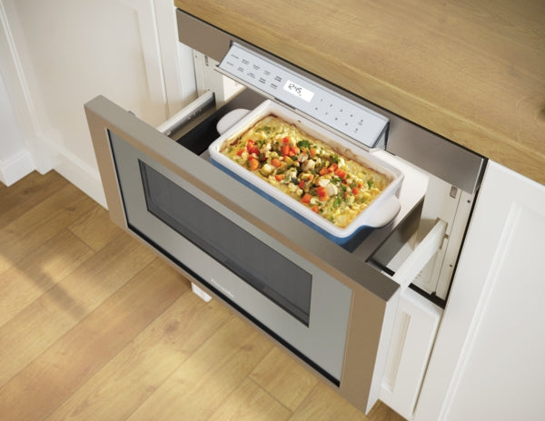 Professional stainless steel microwave drawer with digital control panel showing timer and ceramic dish inside cooking meal
