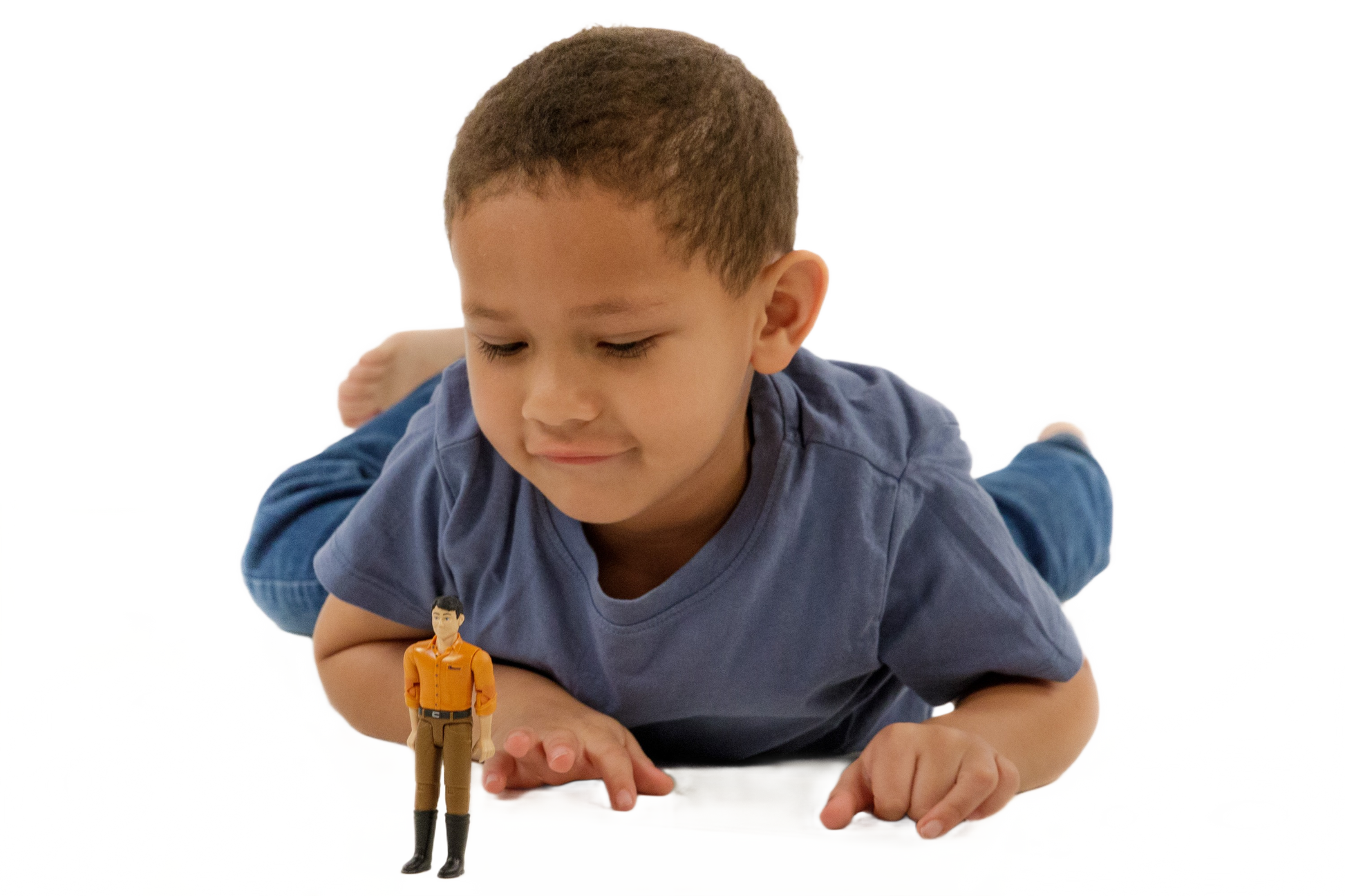 Child wearing blue shirt lying down and playing with Bruder 60007 man toy figure for imaginative play