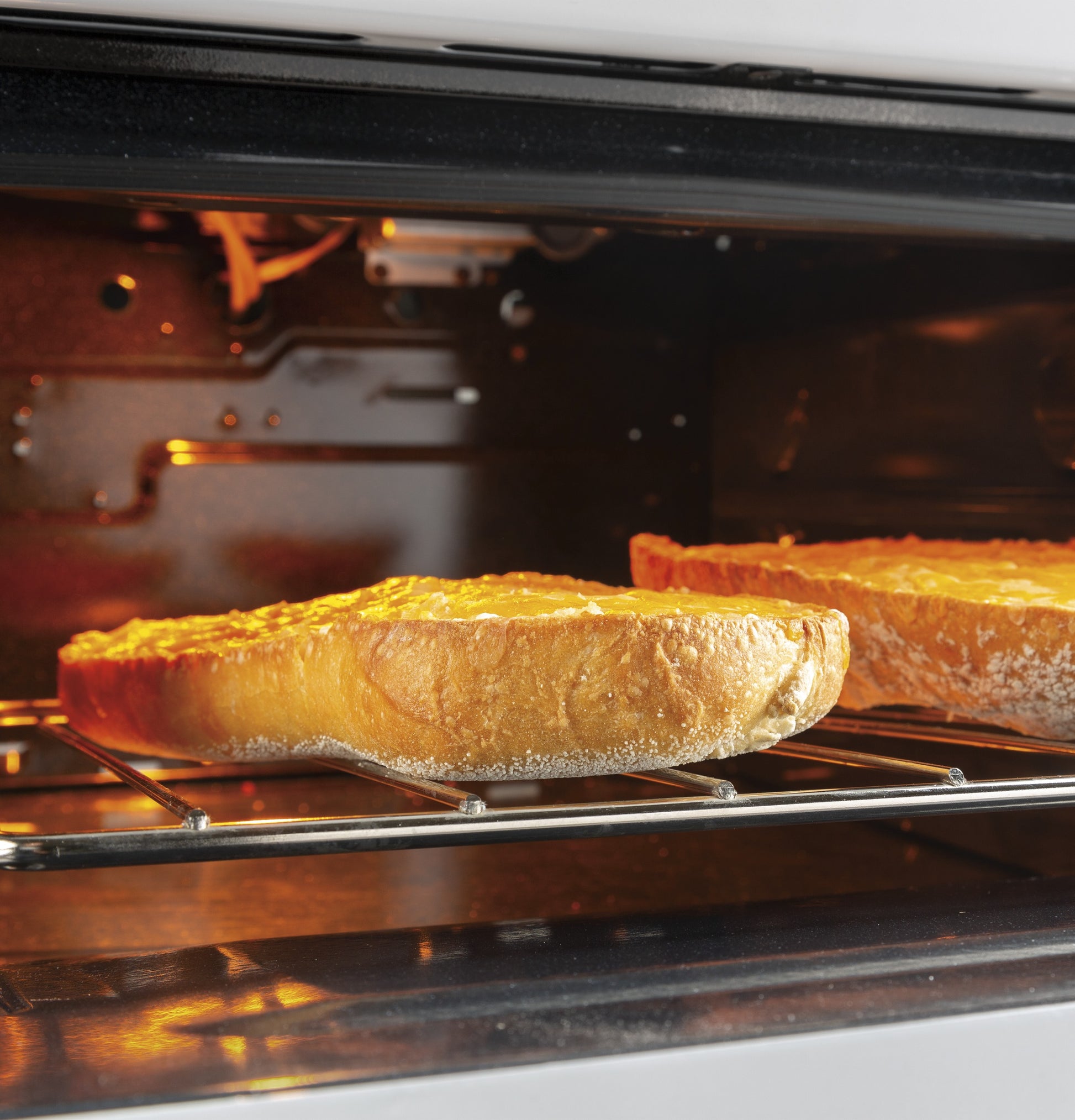 Two pies baking inside the oven of a front-control free-standing gas range in a modern kitchen setting