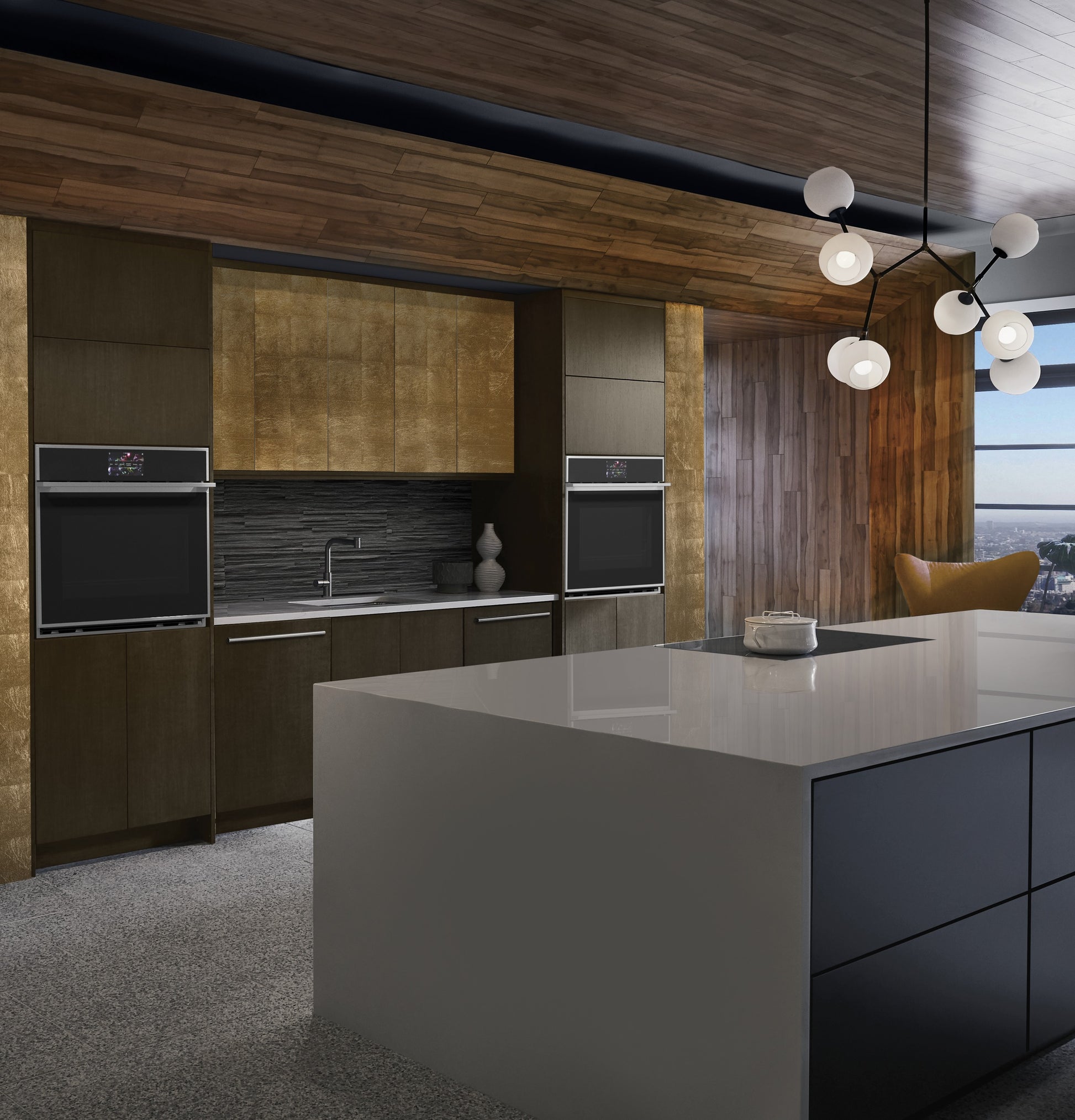 Contemporary kitchen with dual minimalist wall ovens, dark cabinetry, gold accents, large white island, and pendant lighting in appliances collection