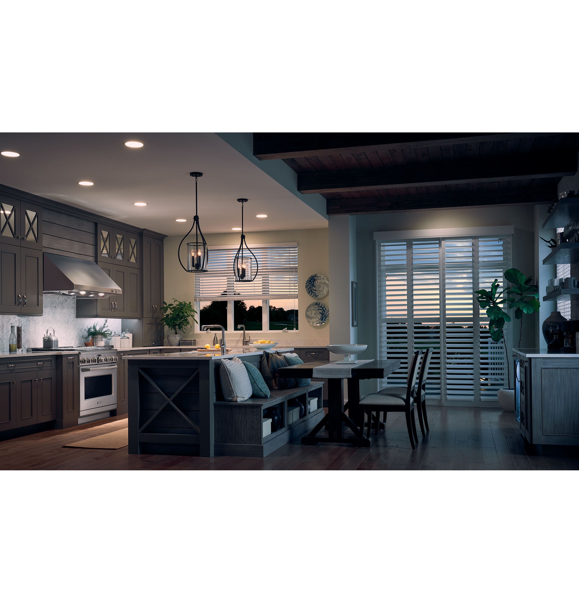 Cozy kitchen with stainless steel hood over stove, dark cabinetry, island seating, pendant lights, and dining area with shuttered doors