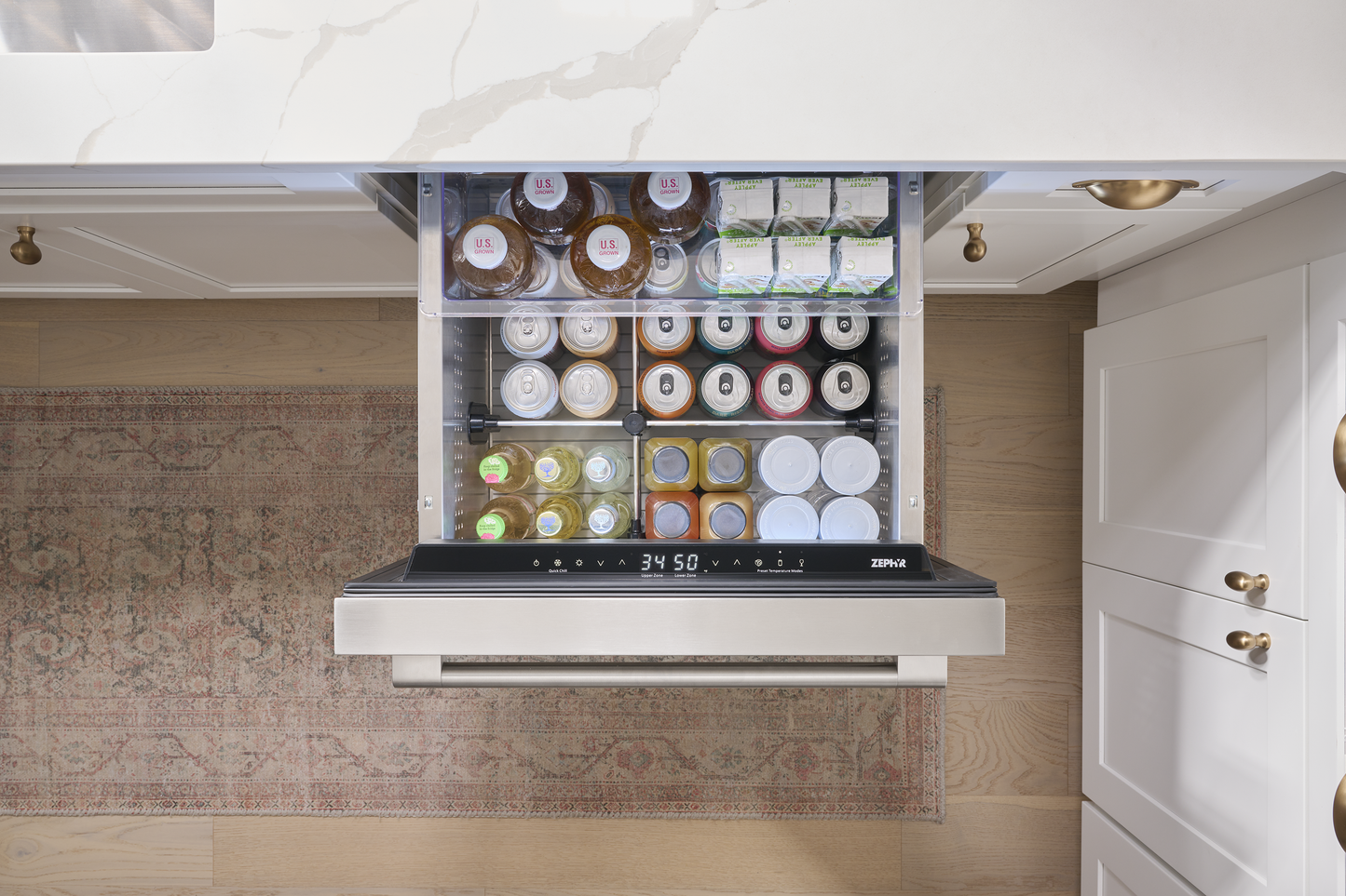 Under-counter stainless steel refrigerator drawer open with organized beverages and snacks in kitchen appliances collection