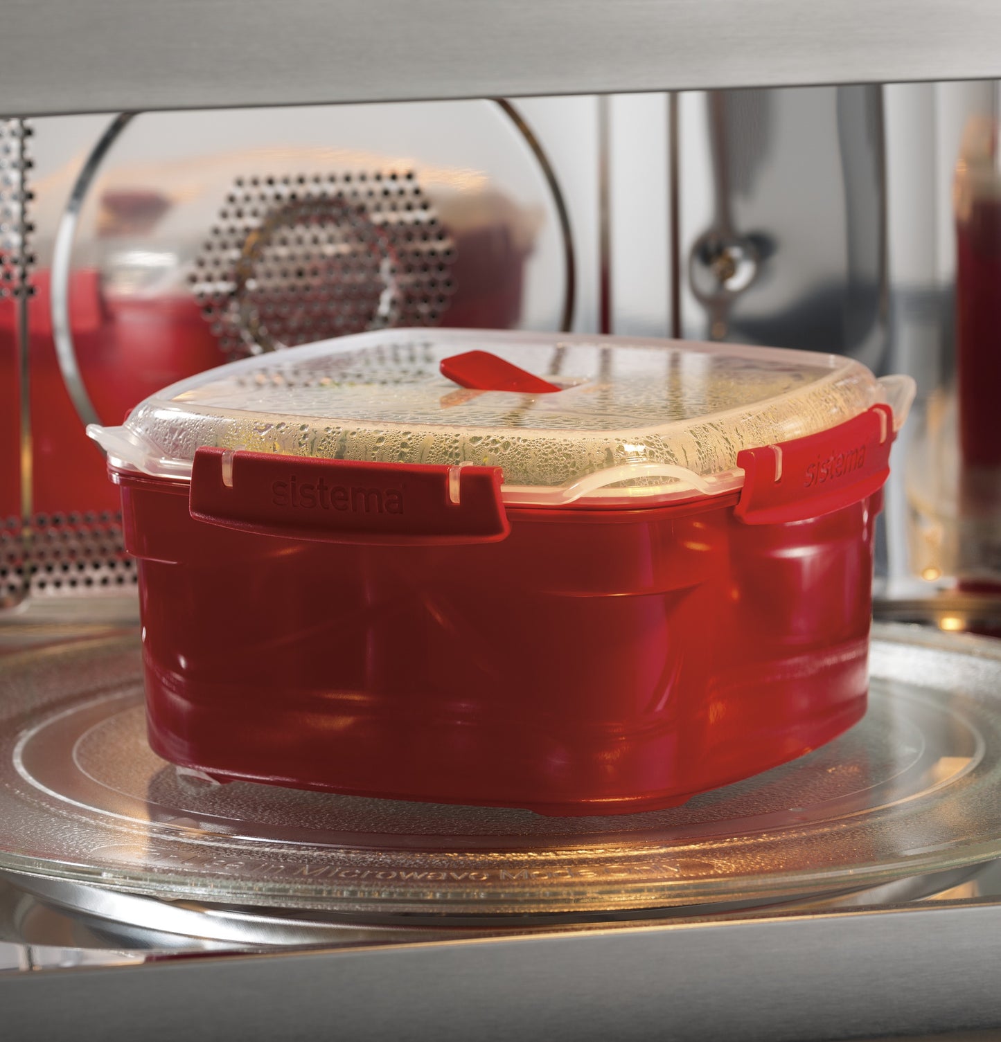 Red microwave-safe container with a vented clear lid warming inside a built-in microwave oven in kitchen appliances collection