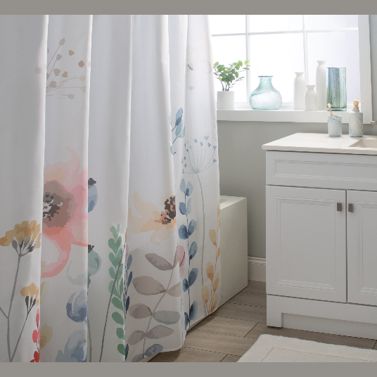 Bathroom with white cabinetry and soft-colored floral patterned shower curtain near a window with decorative vases