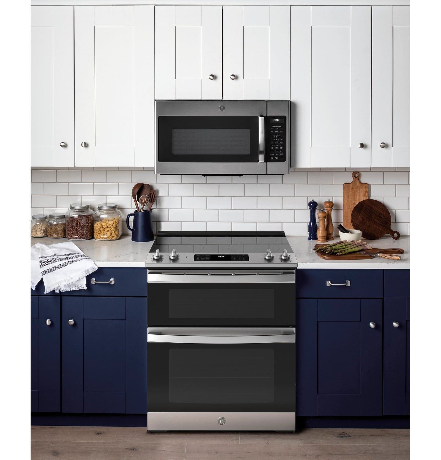 Modern stainless steel slide-in electric double oven range installed in kitchen with white and navy blue cabinetry