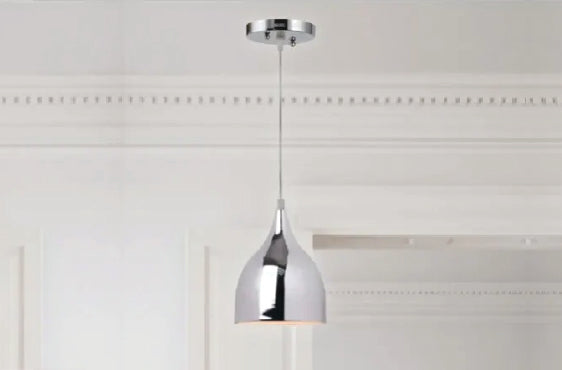 Minimalist pendant light with a polished chrome finish hanging from a white ceiling in a room with classic molding details.