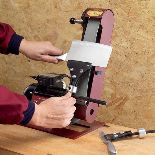 Hands sharpening a knife using a red bench-mounted belt sharpener for precise edge honing in tools and home improvement