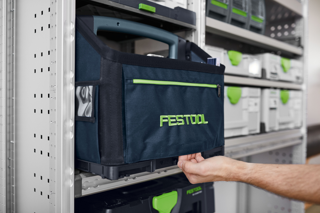 Navy blue and green Festool Systainer tool bag stored on a metal workshop shelving unit for tool organization