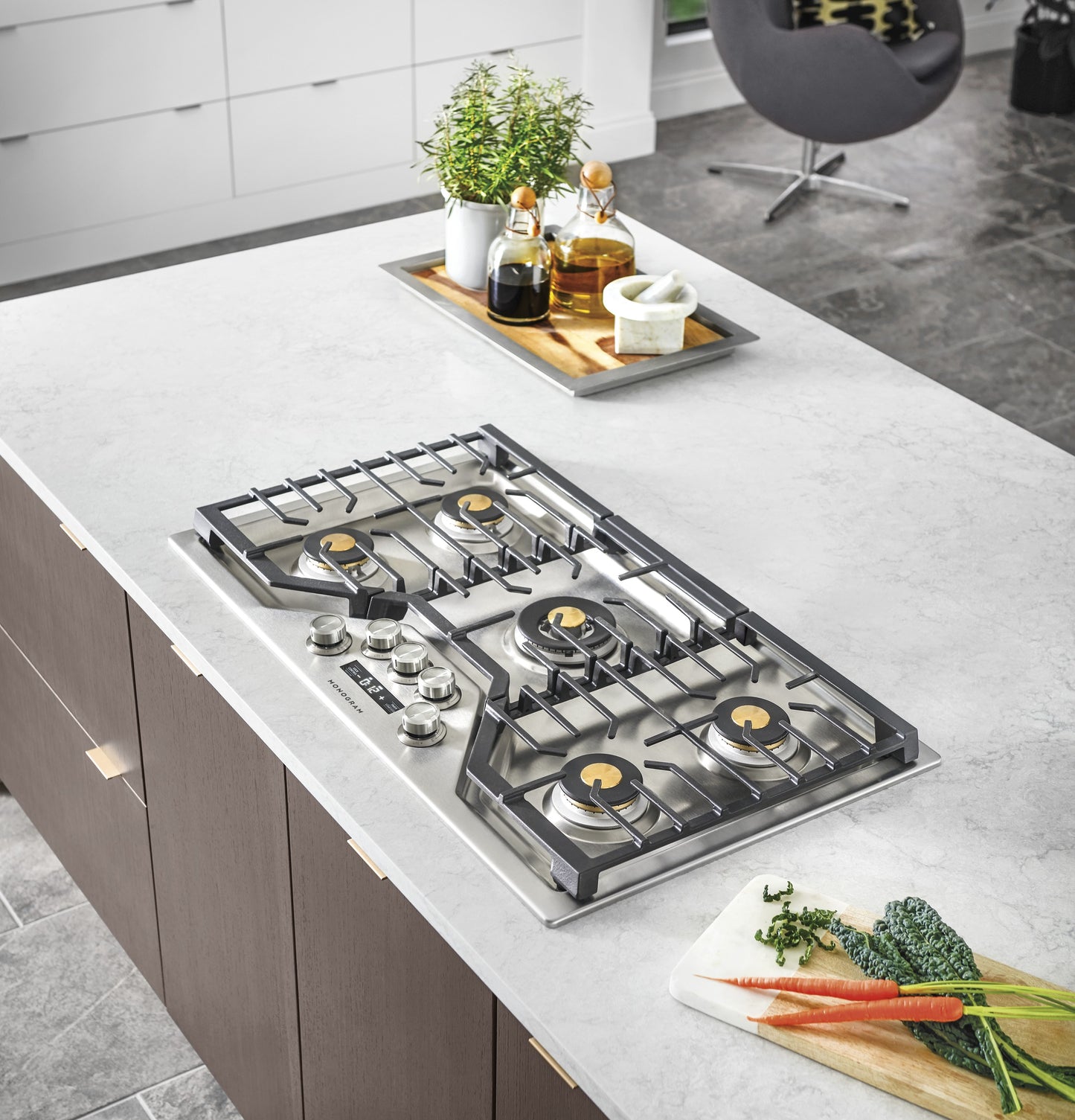 Modern stainless steel gas cooktop with brass burners and cast iron grates in contemporary kitchenware setting