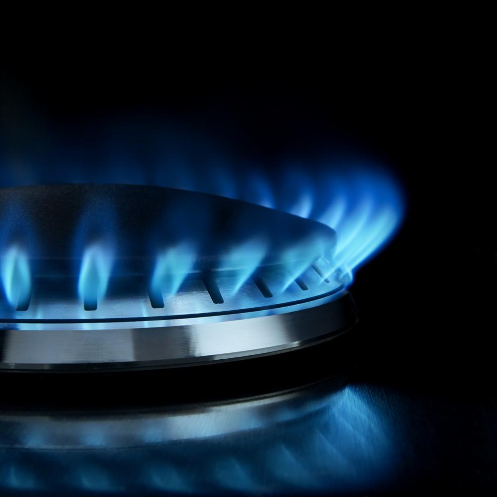 Close-up of blue flame burning on stainless steel gas cooktop burner from kitchen appliances collection