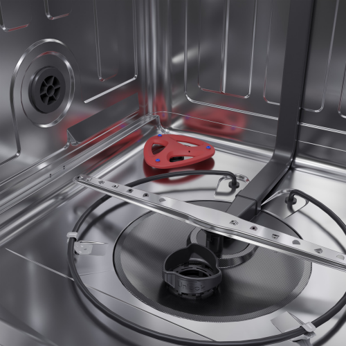 Interior view of stainless steel dishwasher bottom with circular spray arm and red accessory tool for kitchen appliances.