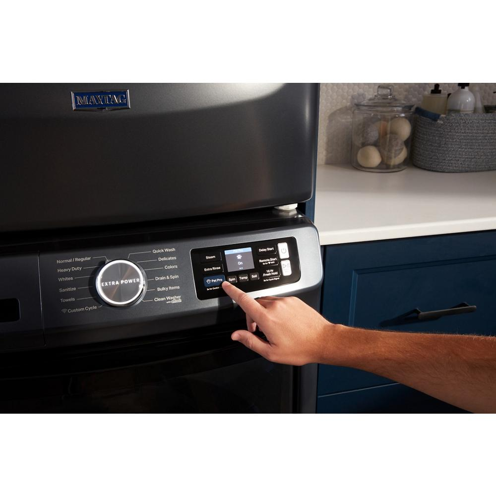 Hand selecting Pet Pro option on digital control panel of dark front load washer in kitchen setting with blue cabinets