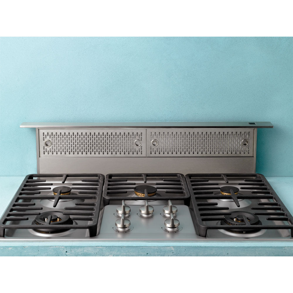 Stainless steel downdraft vent system installed behind gas cooktop with burner controls in modern kitchen setting