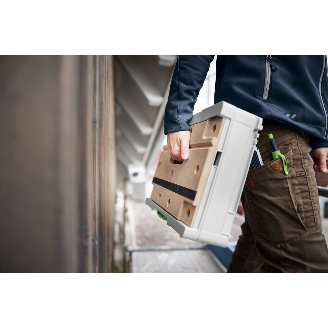 Person holding a compact Festool modular storage system with light wood surface and secure handle, designed for portable workshop organization and woodworking tools.