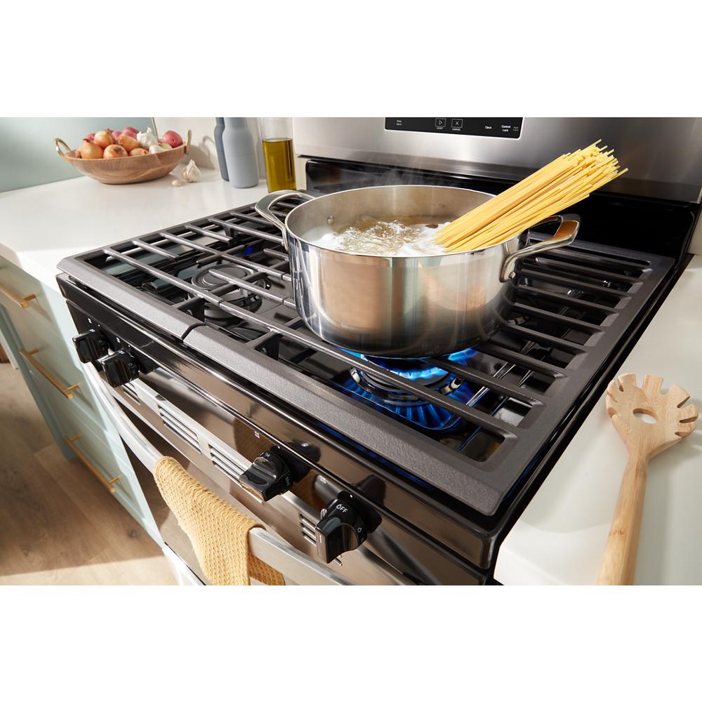 Stainless steel pot boiling water with spaghetti on blue flame of 30-inch gas range in kitchen setting