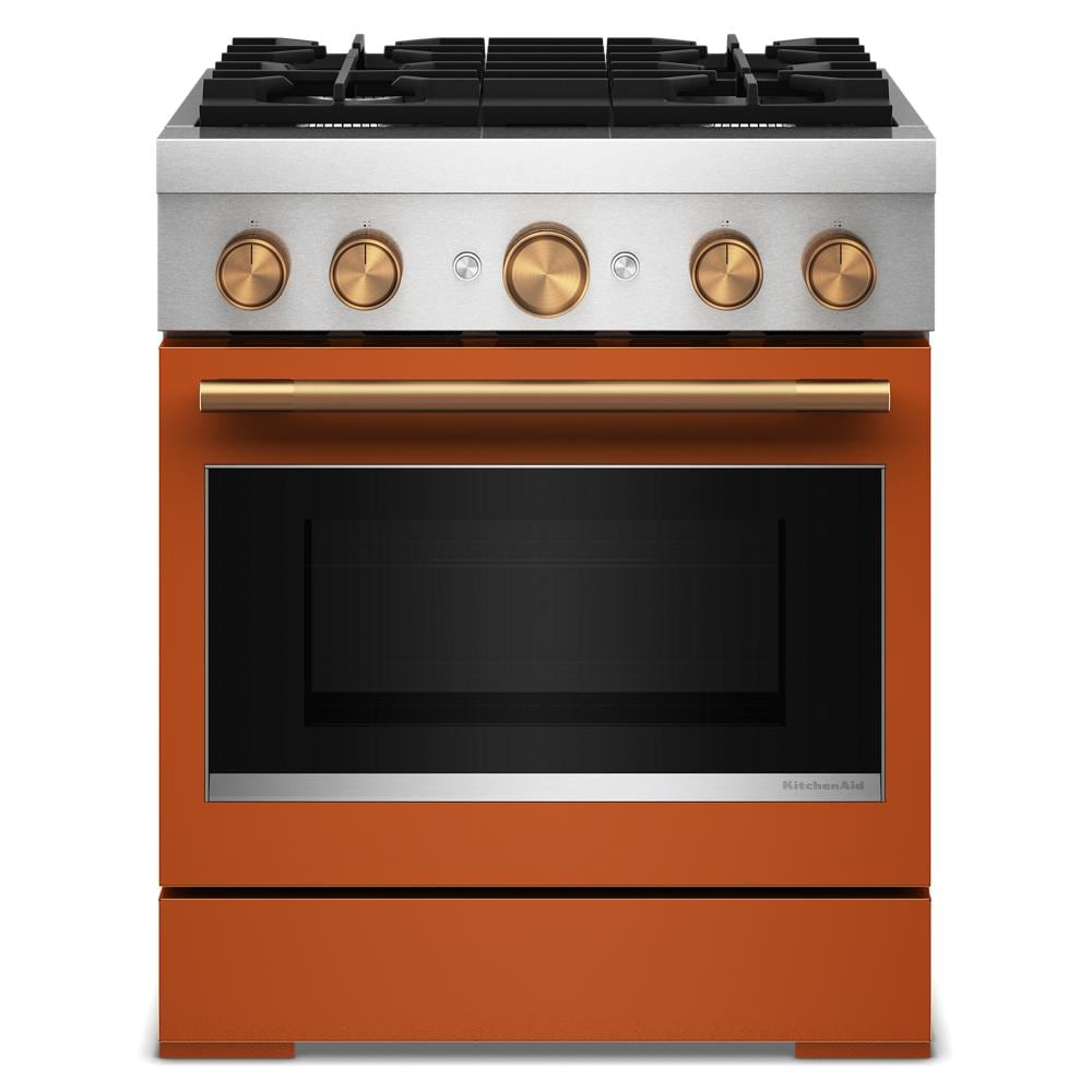 Front view of orange and stainless steel dual fuel range with four burners and brass control knobs in appliance setting