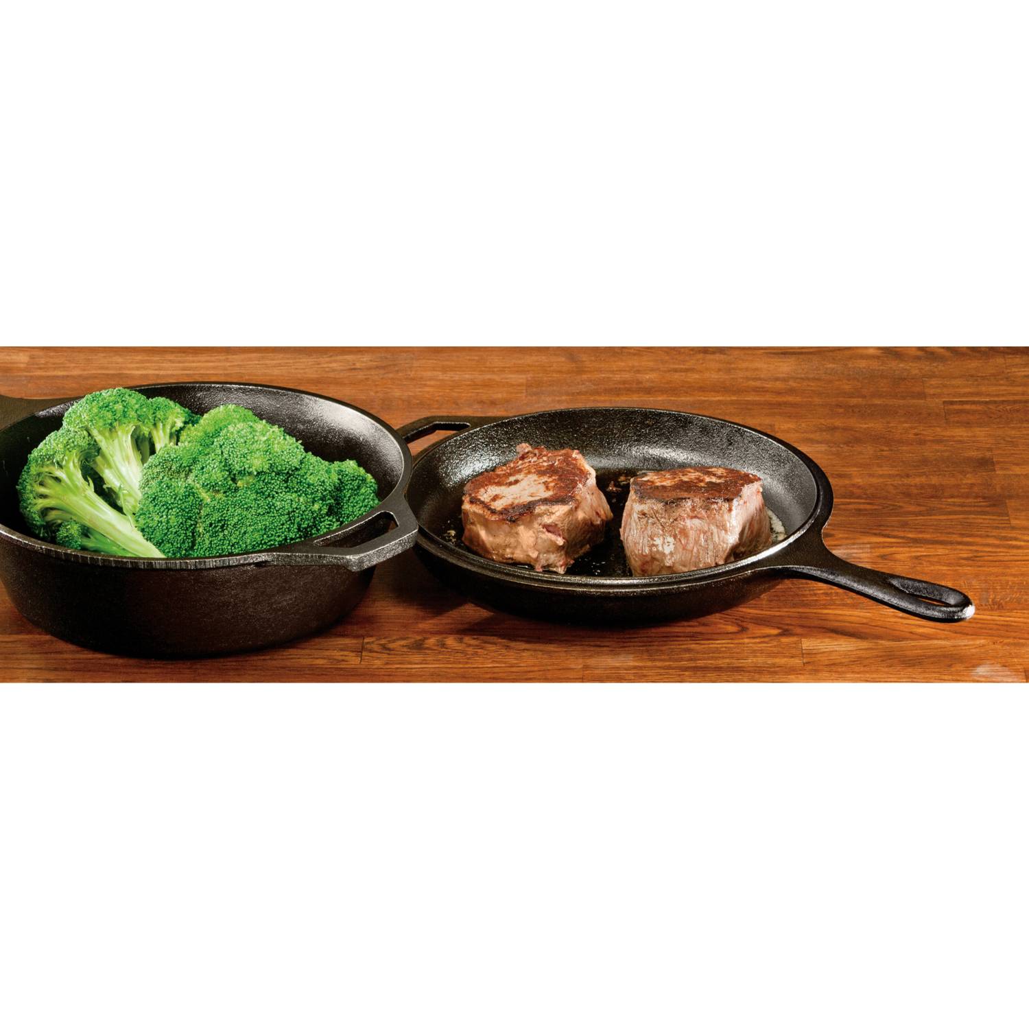 Black cast iron combo cooker with fresh broccoli and seared steak pieces on a wooden surface for home cooking
