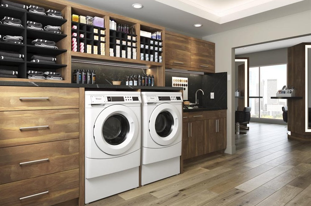 White commercial front-load washer and dryer set in wood cabinetry with black countertop in modern laundry room from Dryers collection