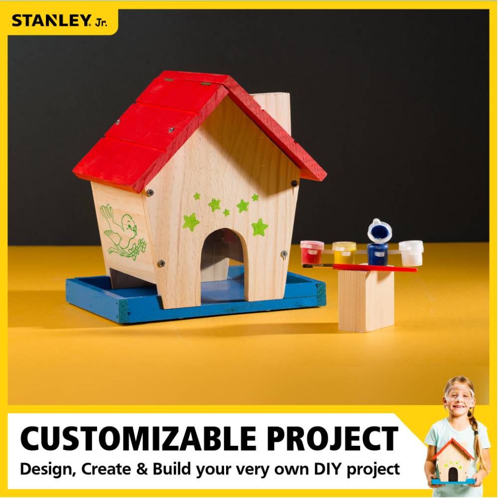 Wooden DIY bird feeder with red roof, blue base, green star decals, and small paint pots for home improvement projects