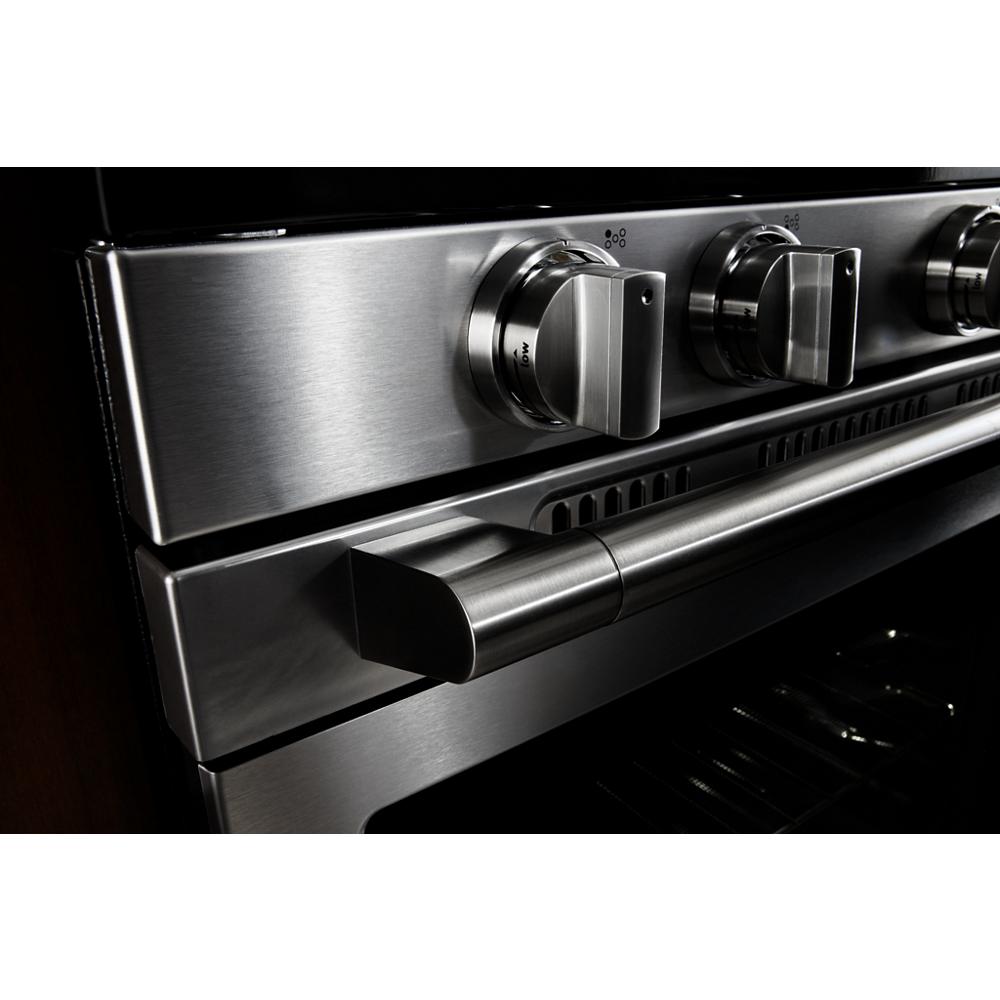 Close-up of stainless steel control knobs and handle on a 30-inch wide electric range for kitchen improvement.