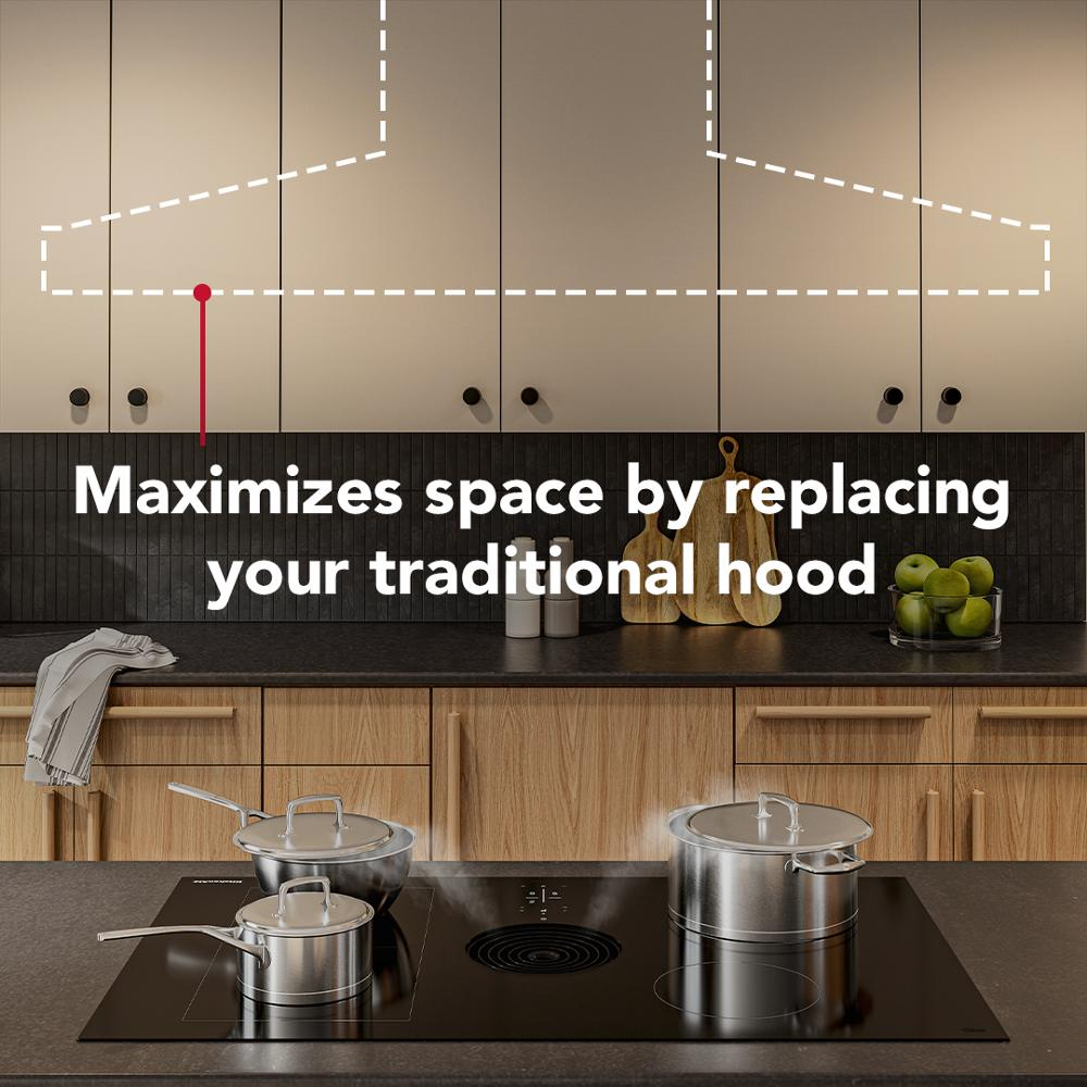Black induction cooktop with downdraft vent installed in wooden kitchen island, pots on heating zones visible