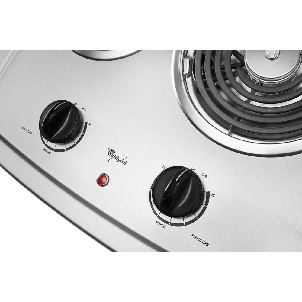 Close-up of stainless steel electric cooktop control panel with two black heat adjustment knobs and indicator light
