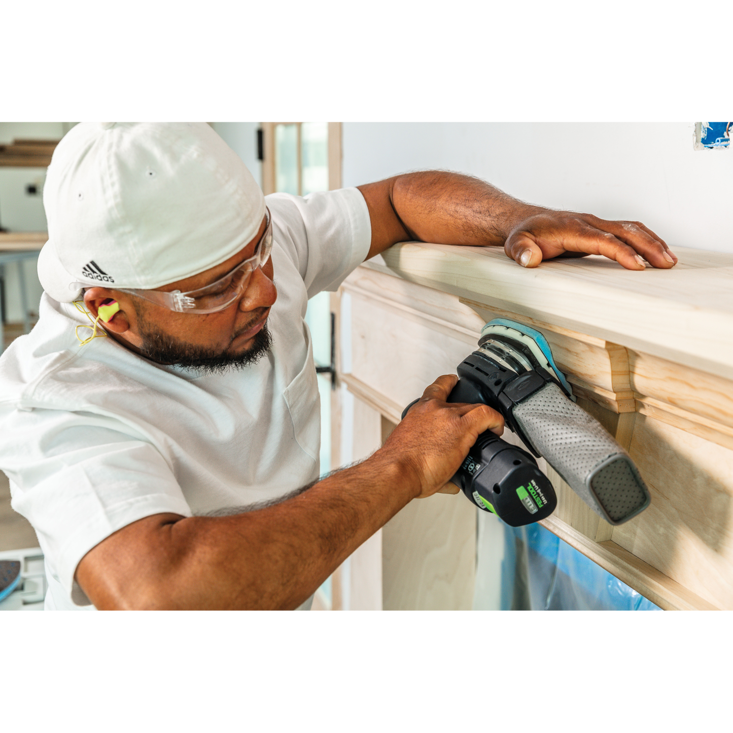 Craftsman using power sander with delta abrasive for precise woodworking on decorative wooden molding in tool accessories collection