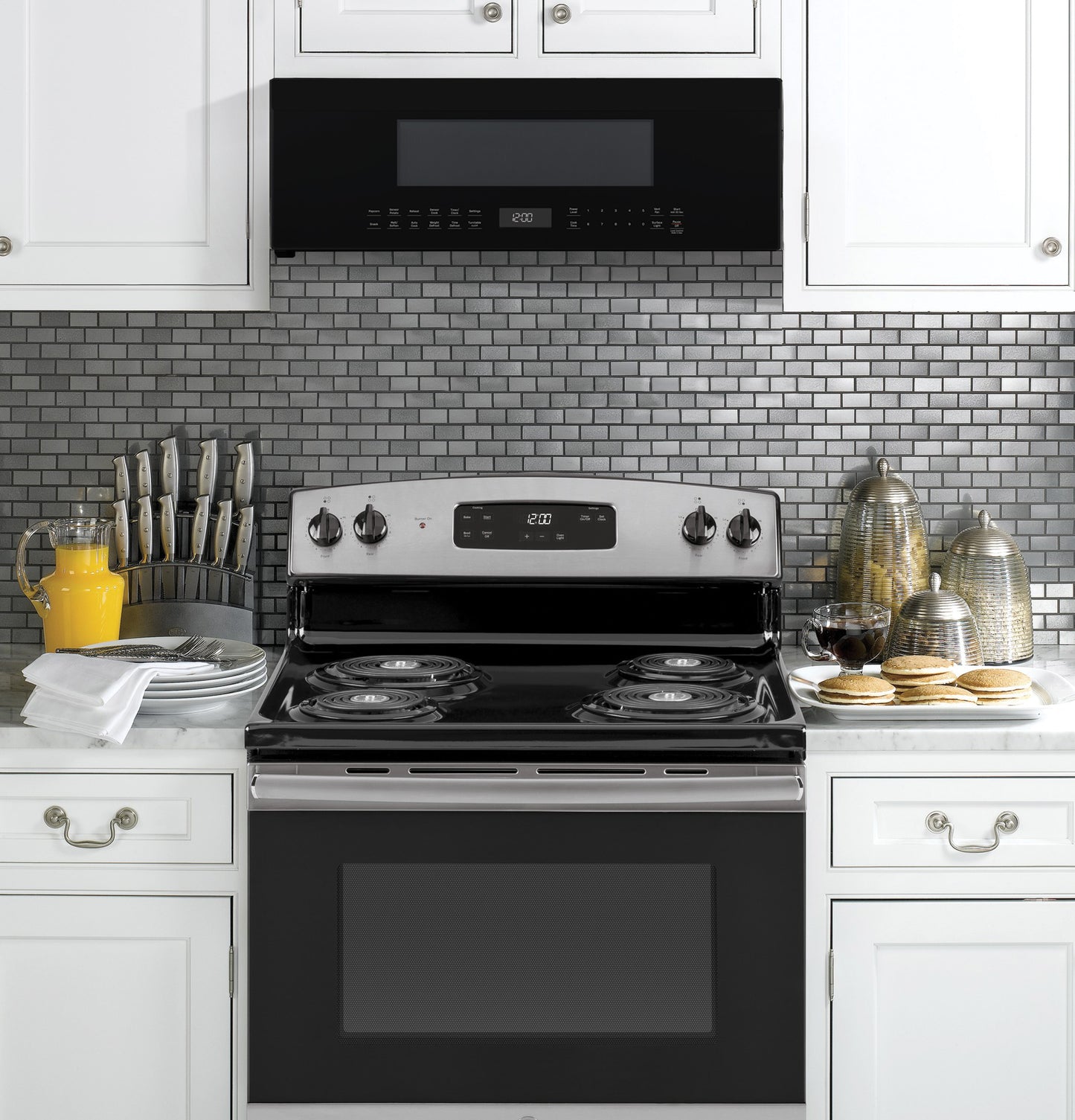 Over-the-range black and stainless steel microwave oven installed above stove in modern kitchen appliances setting