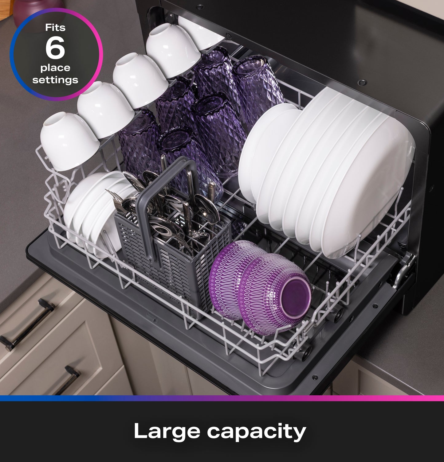 Open compact dishwasher loaded with plates, glasses, and cutlery showing large capacity for six place settings on countertop