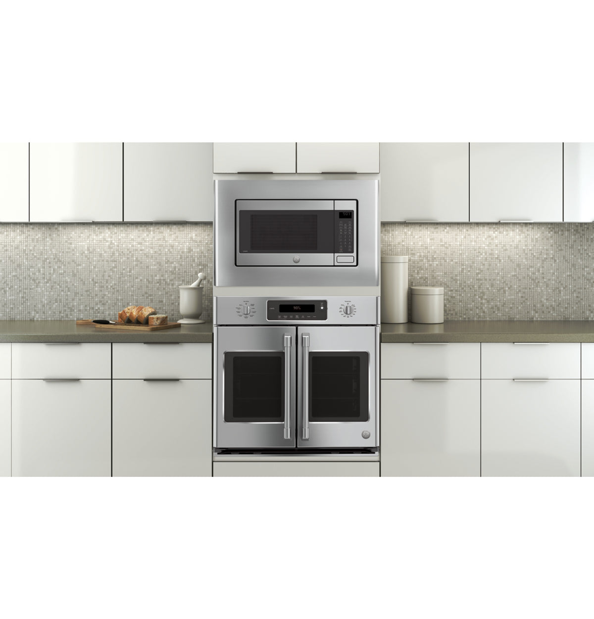 Modern kitchen with stainless steel microwave and double oven built-in within white cabinetry and gray countertop accents