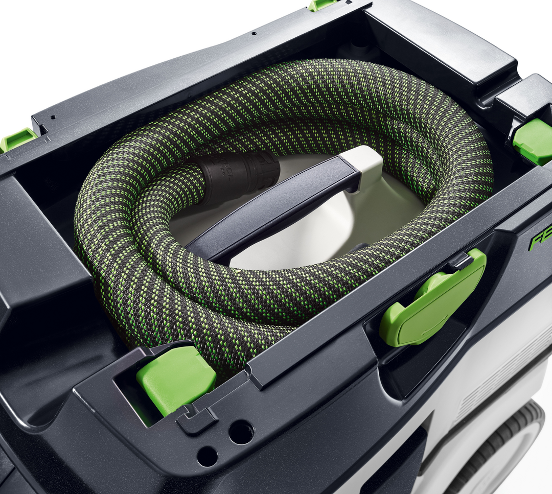 Top view of Festool dust extractor showing coiled green and black hose stored inside compact tool case for woodworking use