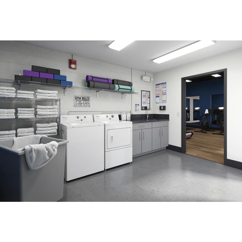 Laundry room with white commercial top-load washer and dryer, gray cabinets, folded towels, and mats, adjacent to fitness area.