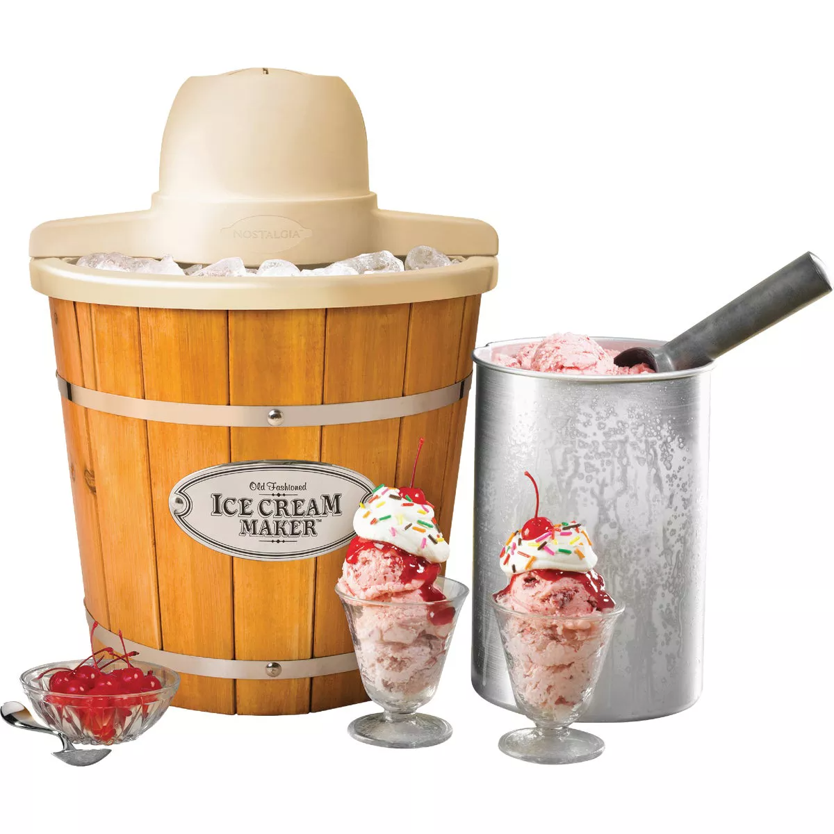 Wooden electric ice cream maker with ice, metal freezing canister, and two scoops of strawberry ice cream sundaes with cherries and sprinkles