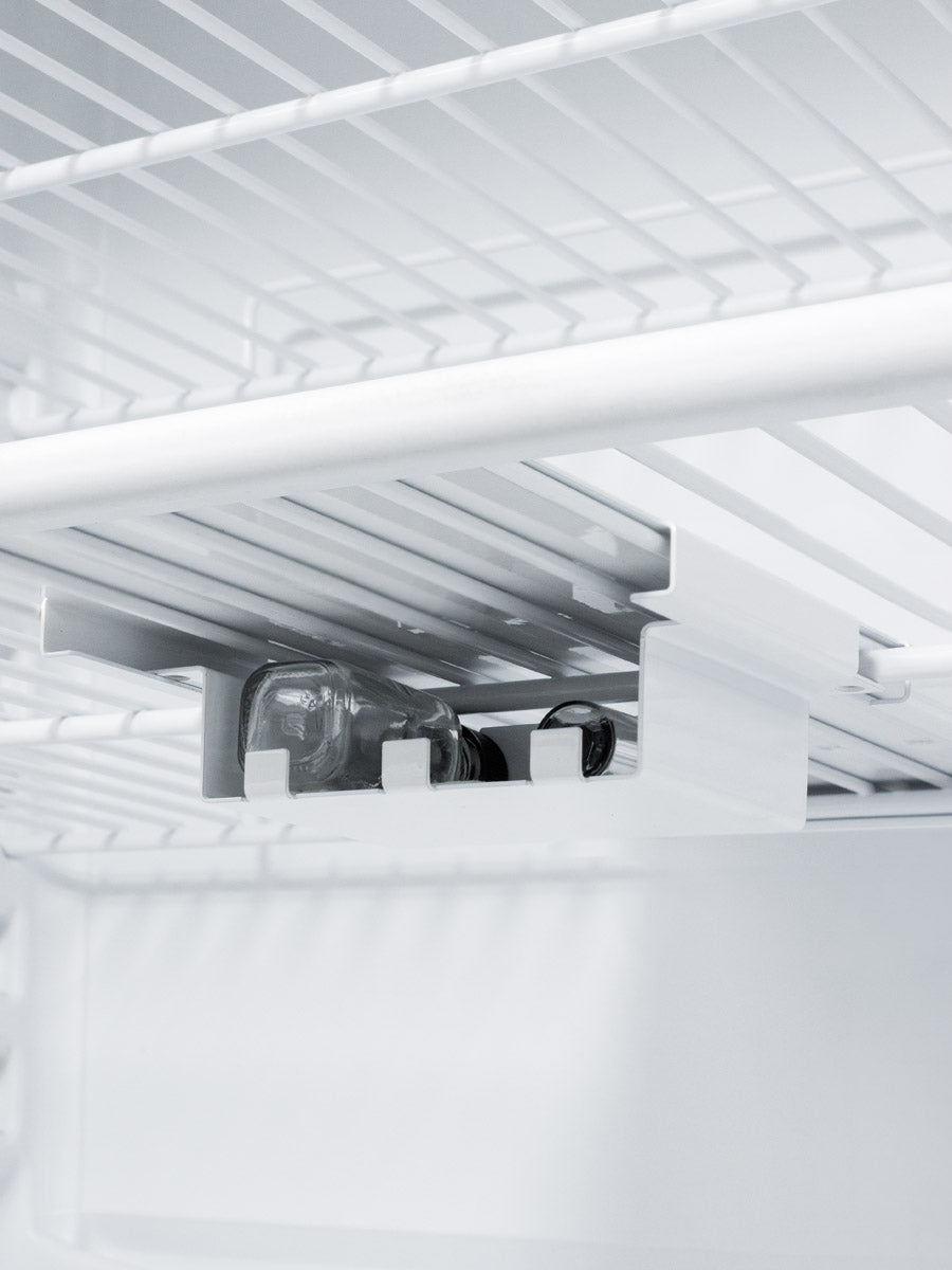 Interior view of a white wire shelf with a small rack holding two glass medical vials in a built-in refrigerator.