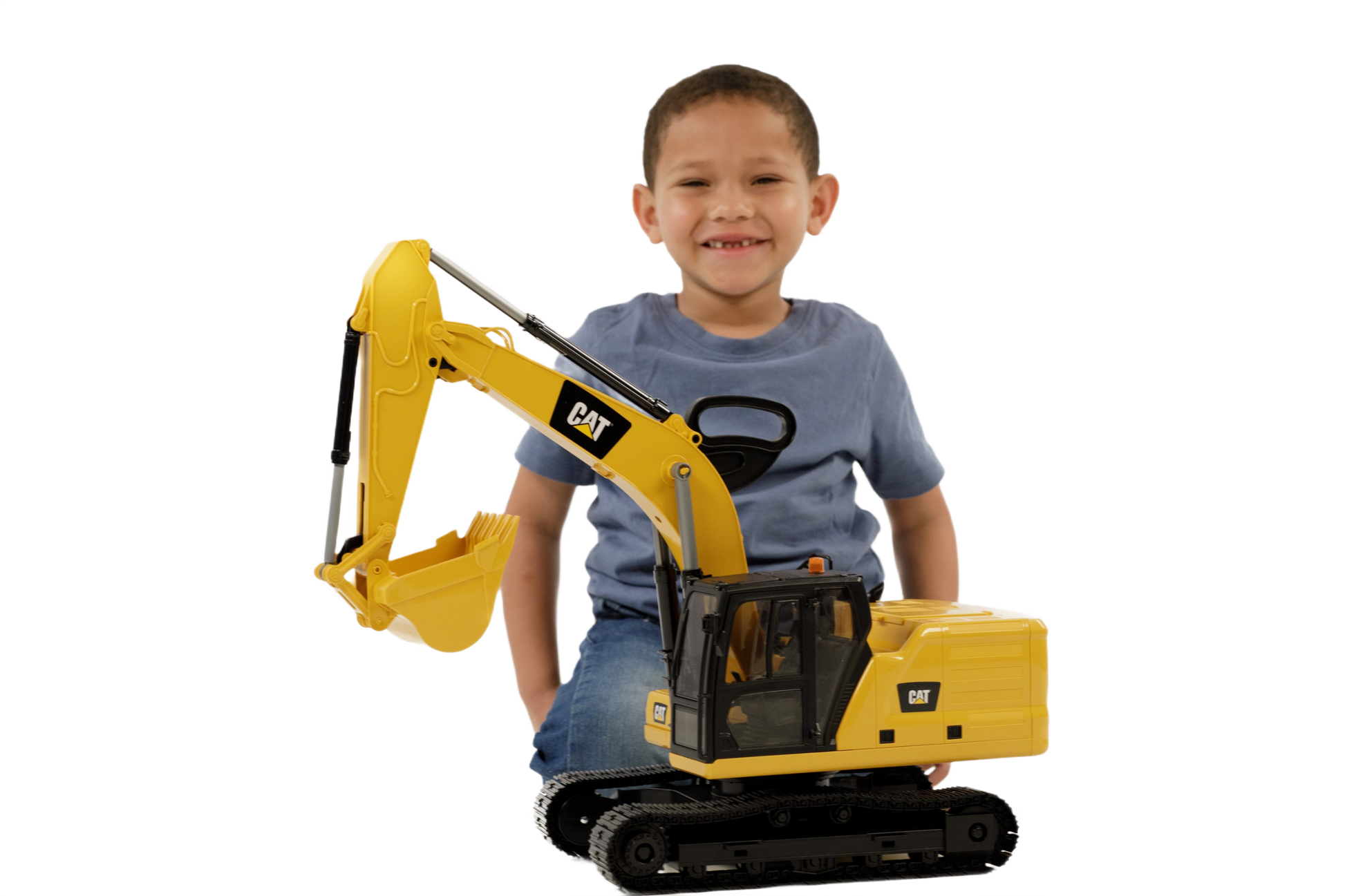 Young child smiling and playing with a large yellow Bruder 02484 CAT Excavator toy on black tracks