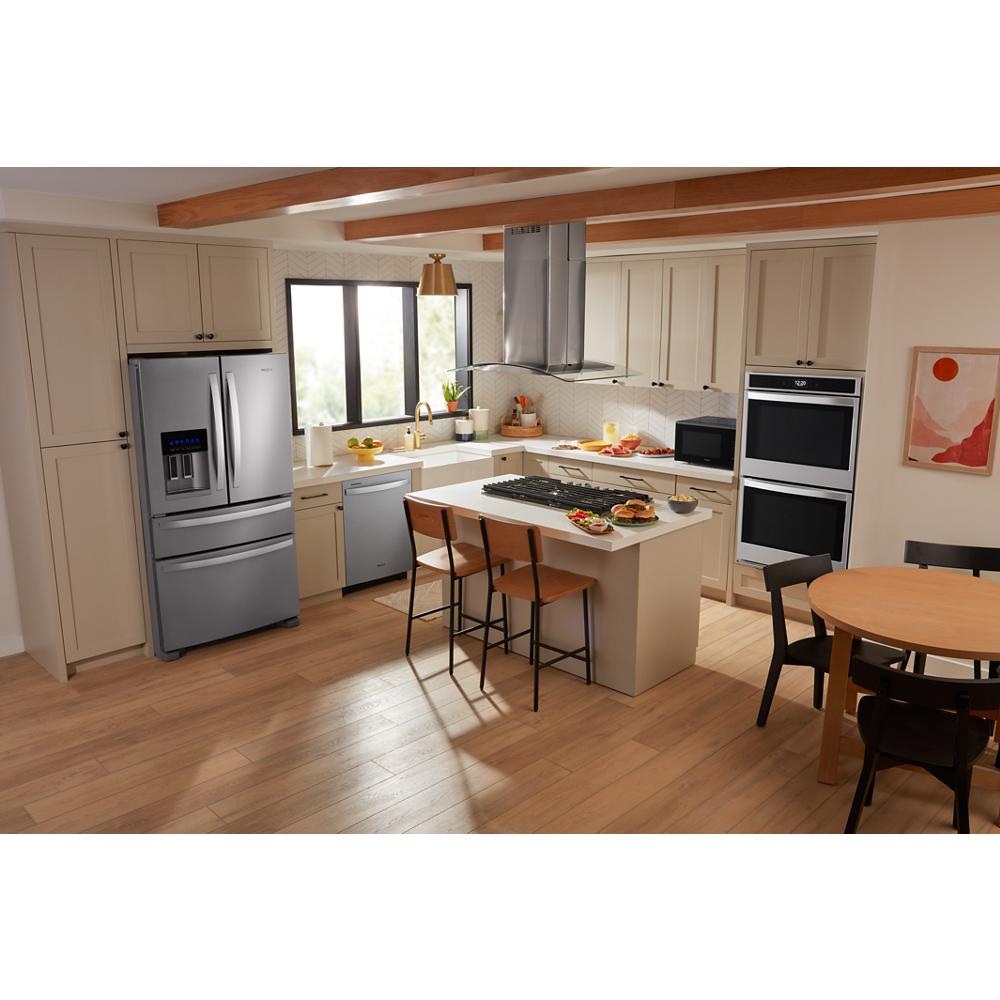 Spacious kitchen with stainless steel refrigerator, built-in ovens, dishwasher, and curved glass island mount range hood