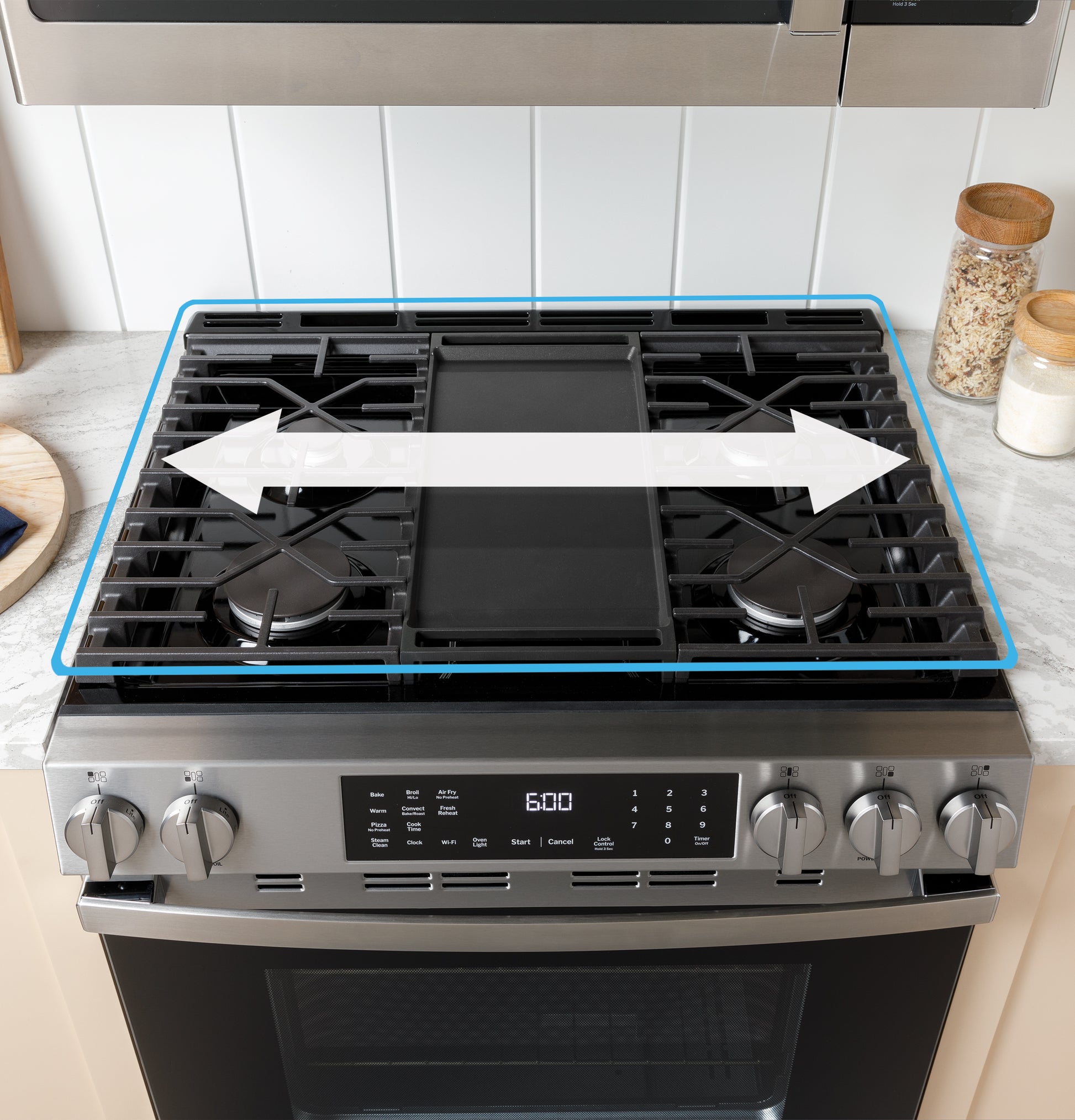 Stainless steel gas cooktop with front controls and central griddle in a modern kitchen setting with white tile backsplash