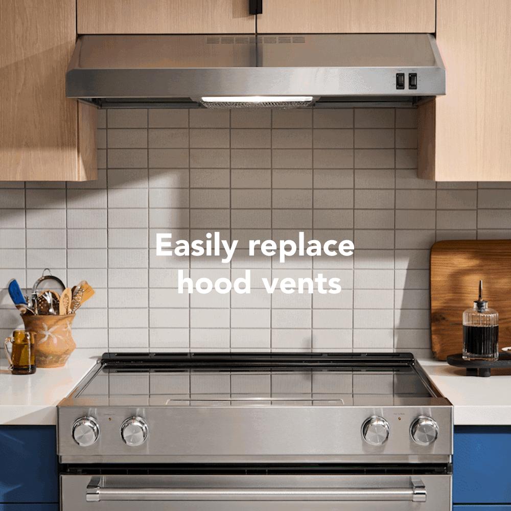 Stainless steel under-cabinet ventilation hood installed above a modern stove in a kitchen with light wood cabinets