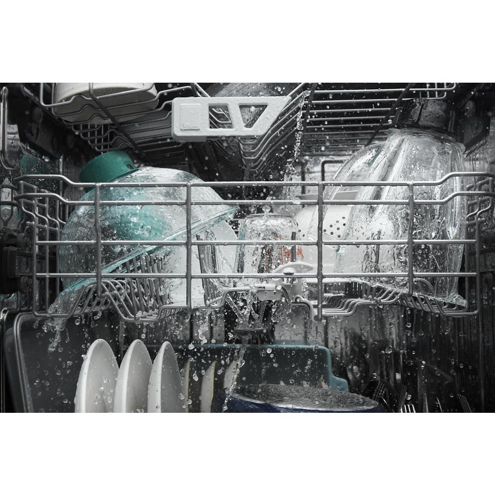 Interior of dishwasher washing clear glassware, plates, and bowls with water spraying inside appliance