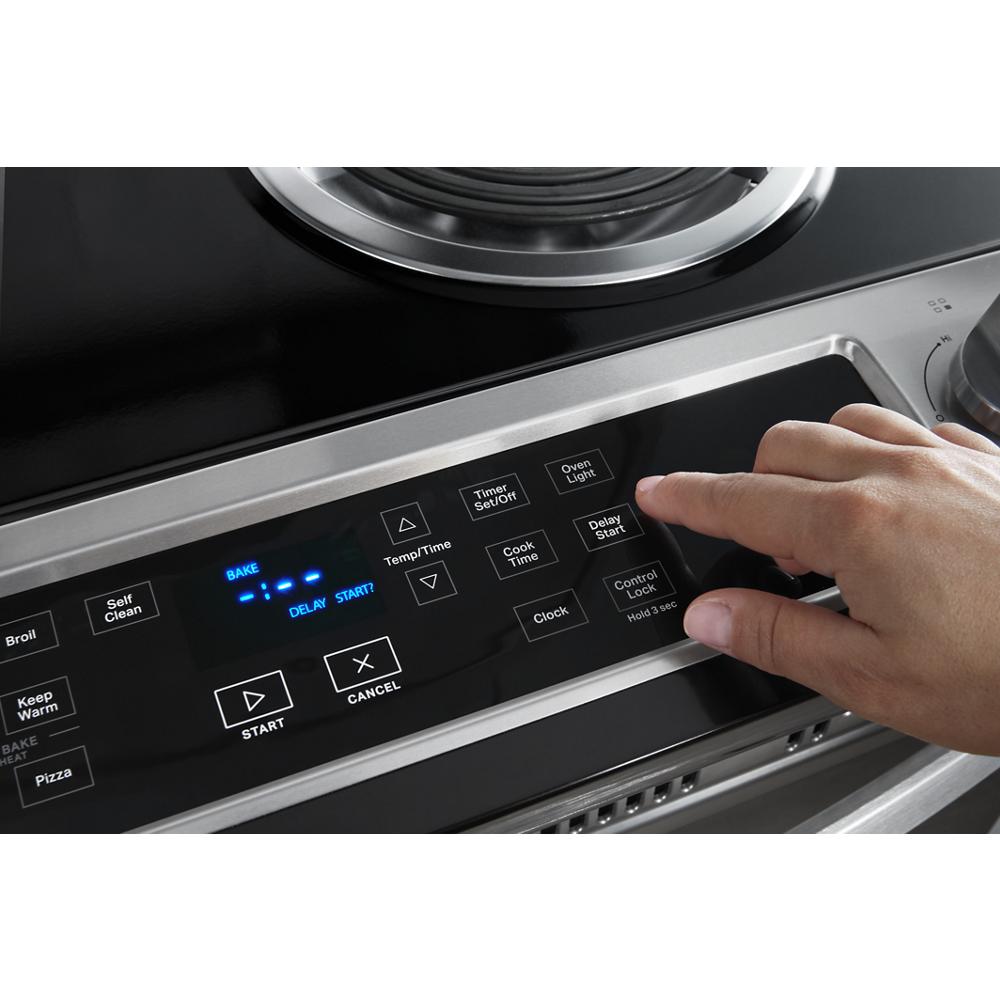 Close-up of hand pressing digital control panel buttons on stainless steel electric range from kitchen appliances collection