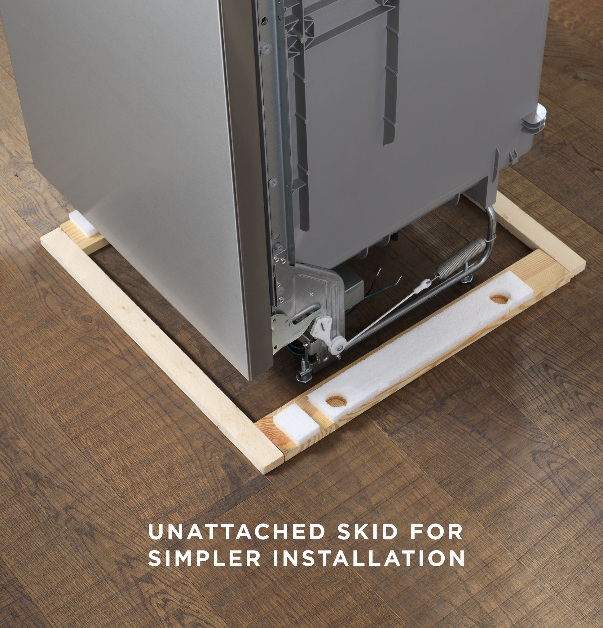 Bottom corner view of a dishwasher with detached wooden skid on hardwood floor for easier installation in appliances collection