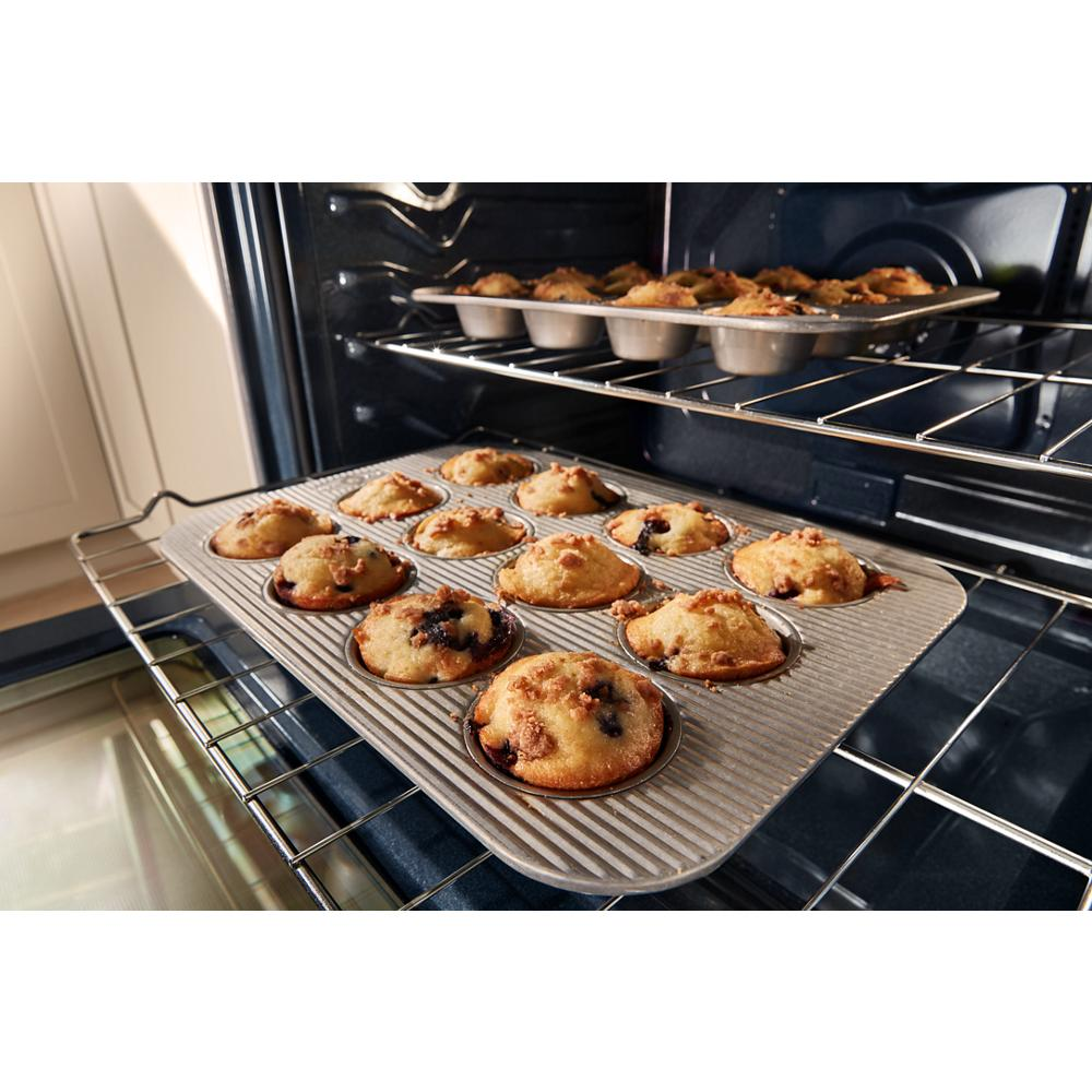 Close-up of a muffin tray with freshly baked blueberry muffins inside an open electric oven, highlighting its cooking performance for ranges and kitchenware collections.