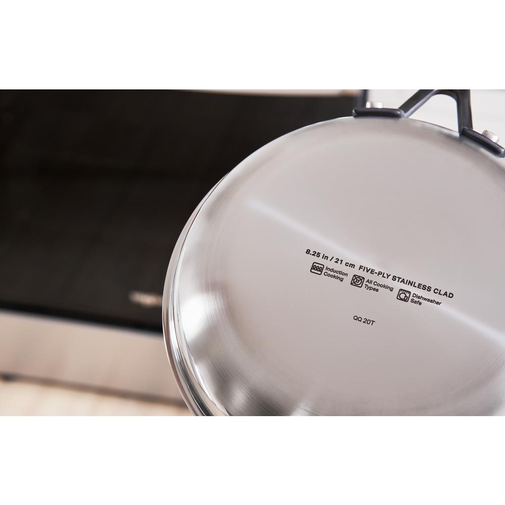 Close-up of the base of a stainless steel five-ply clad pan on a smooth induction cooktop surface