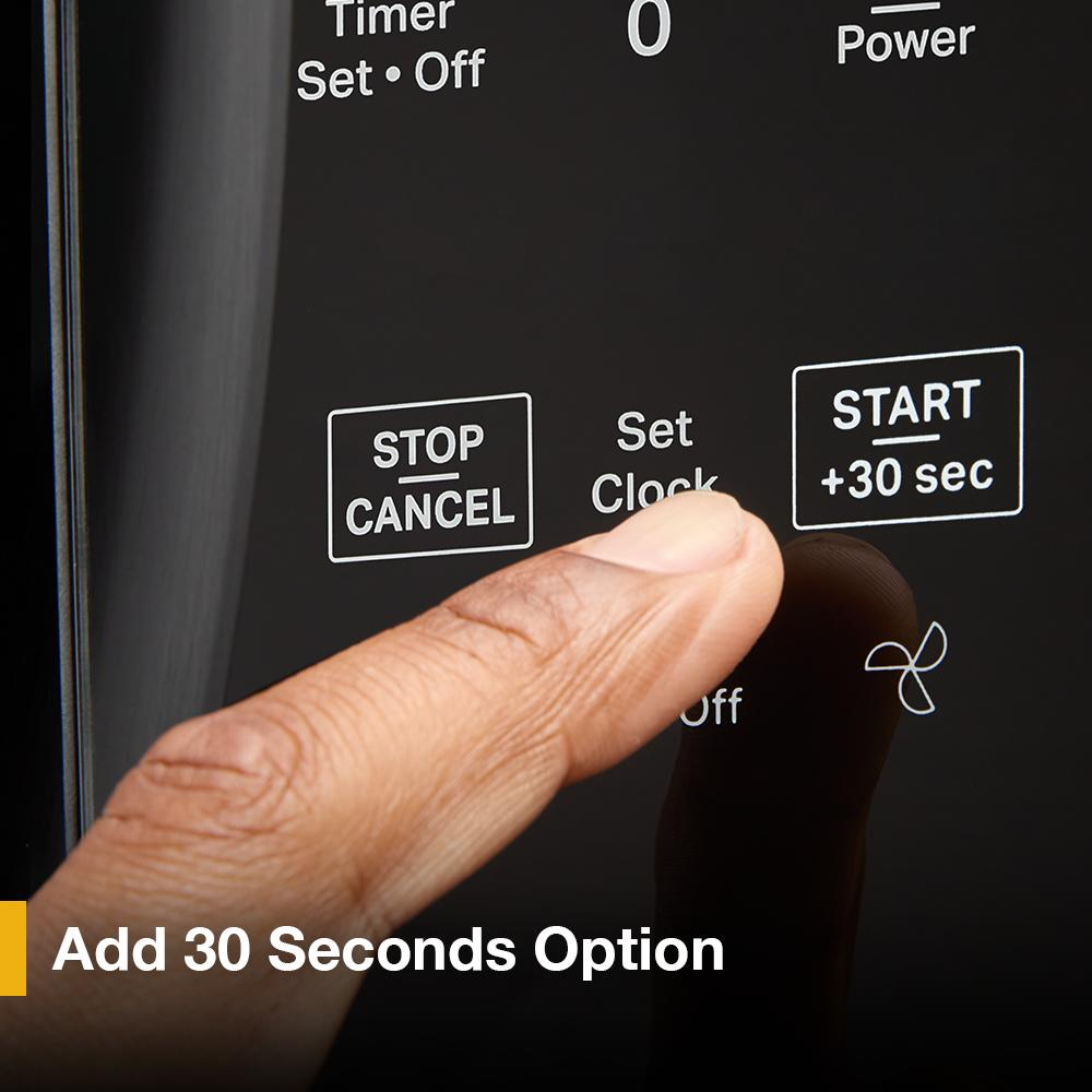 Finger pressing digital control panel button to add 30 seconds on a black over the range microwave in kitchen appliances collection