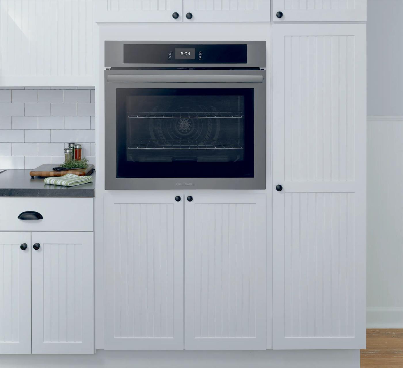 Built-in stainless steel wall oven with touchscreen control panel and convection fan in a modern kitchen setting