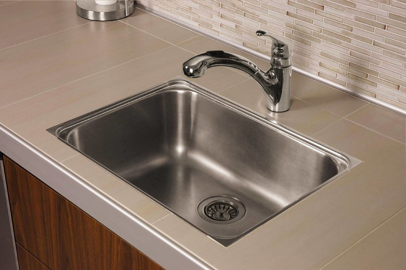 Stainless steel kitchen sink with single-handle chrome faucet set in tiled countertop for home improvement projects
