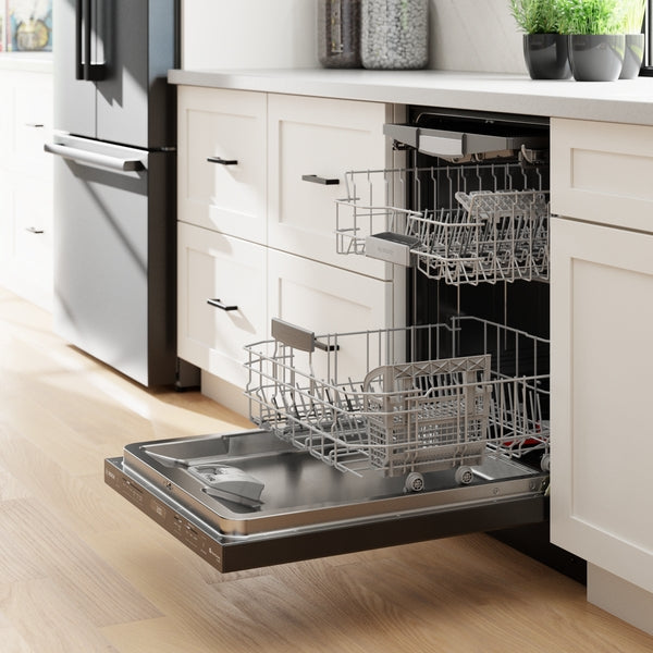 Open brushed black steel dishwasher integrated into white kitchen cabinetry with light hardwood flooring from Bosch appliances collection