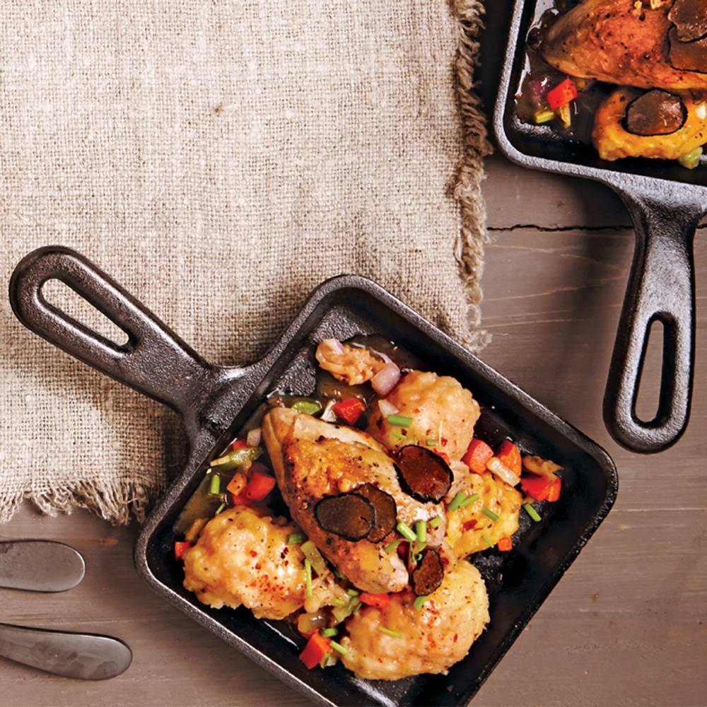 Small cast iron skillet with cooked chicken and vegetables, shown on rustic wooden surface in kitchenware under $50 collection