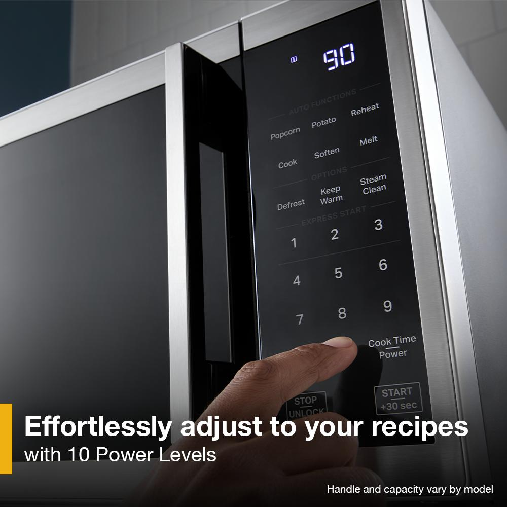 User pressing digital control panel on stainless steel microwave with white LED display in kitchenware collection