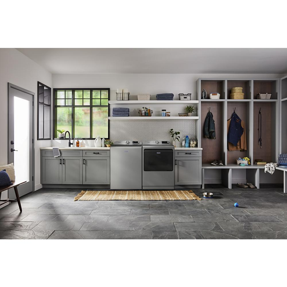 Laundry room with grey top load washer and matching dryer, built-in shelves, and open locker storage with coats and shoes